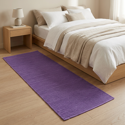 Alfombra morada junto a la cama en un dormitorio acogedor