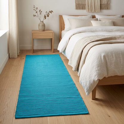 Alfombra turquesa junto a una cama en un dormitorio acogedor