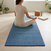 Escena de meditación sobre la alfombra textil, con ambos extremos visibles y luz suave de mañana